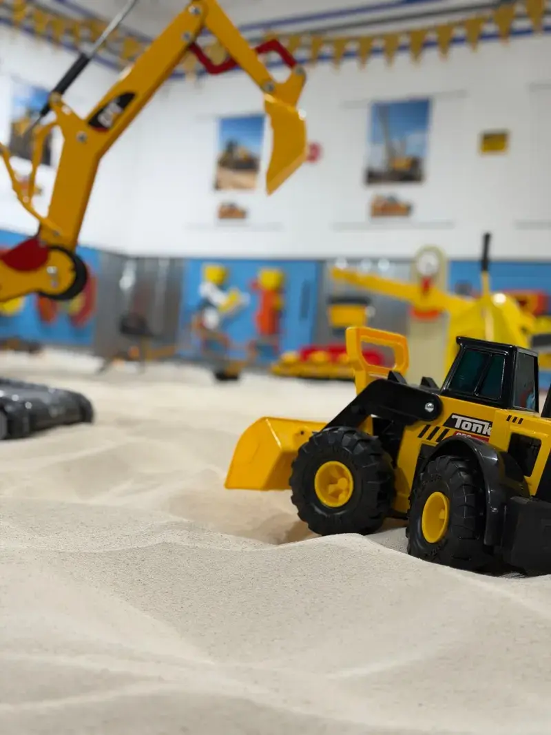 Close view of toy loaders and diggers in the sand