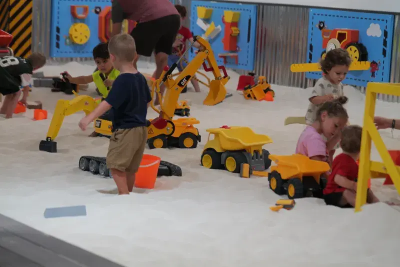Children playing with dump trucks and buckets