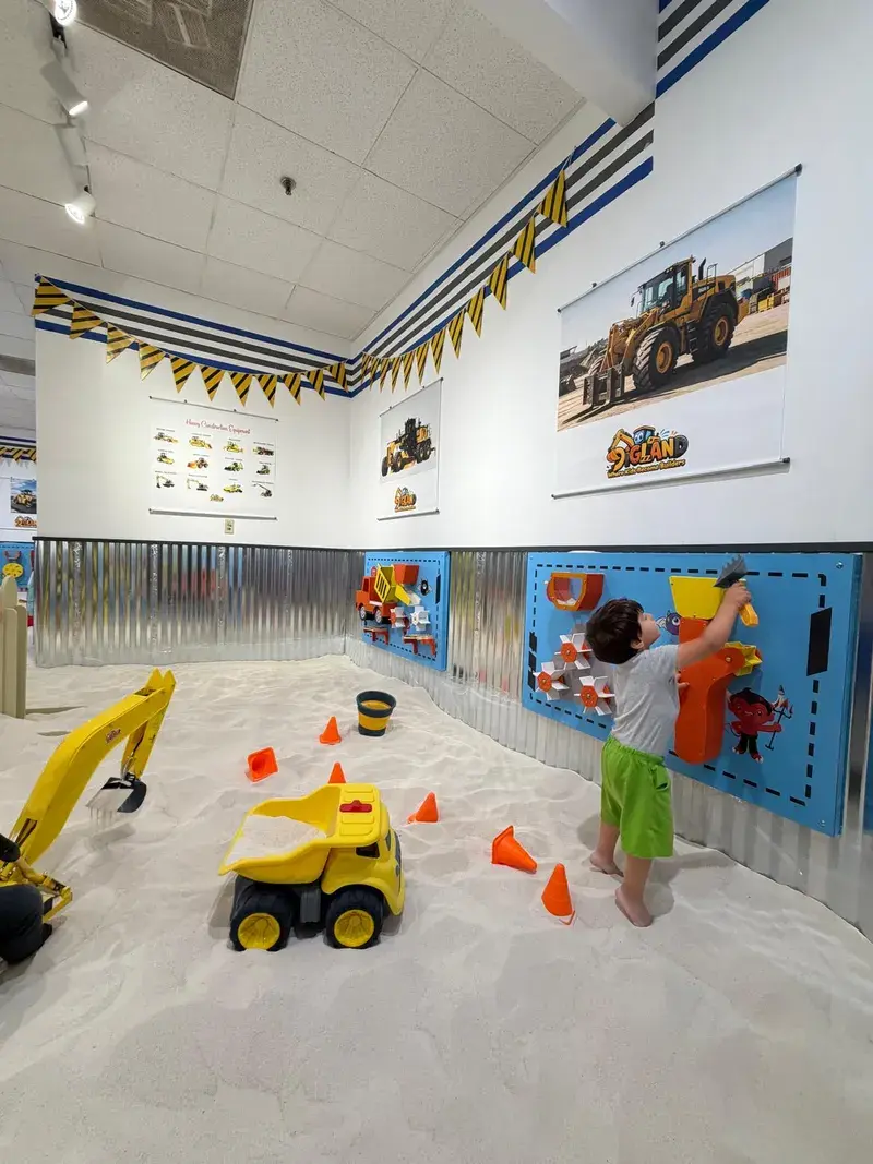 Child reaching for the activity panel beside a dump truck