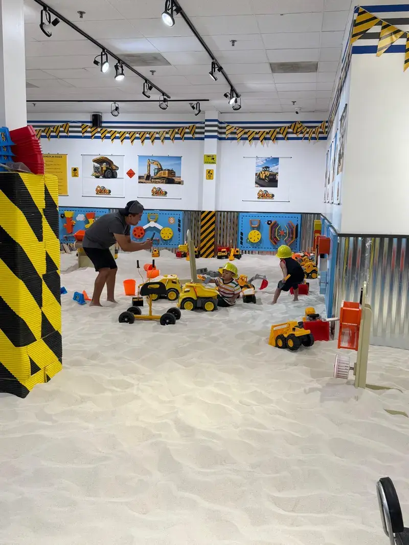 A parent and children digging together in the sand