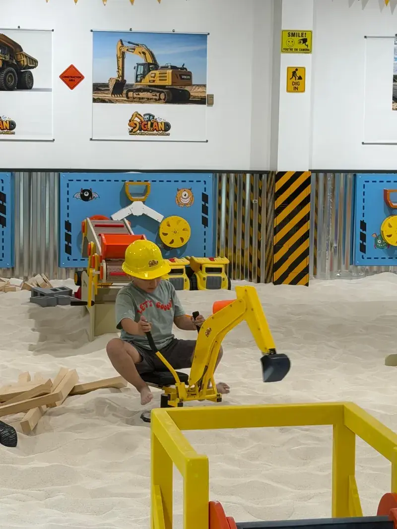Child in a hard hat driving a ride-on digger