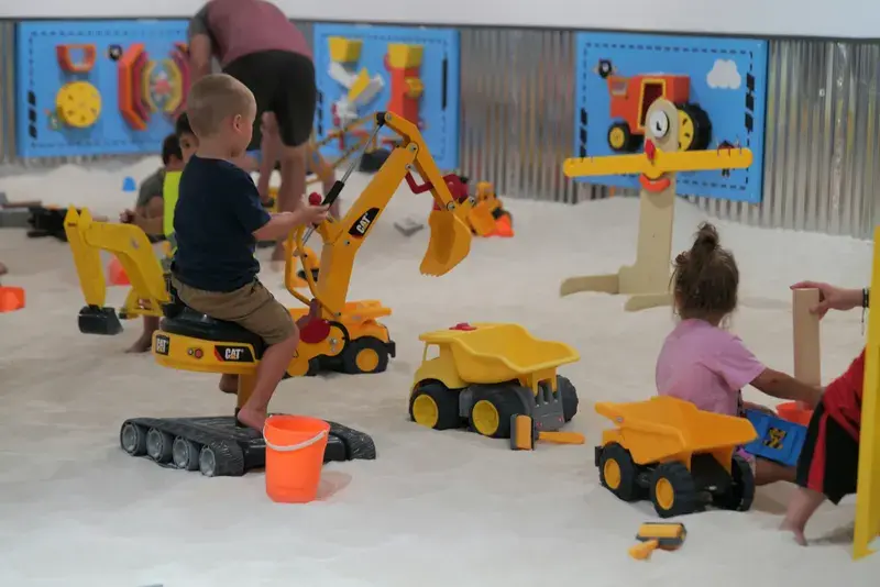 Boy sitting on a ride-on excavator in the sand