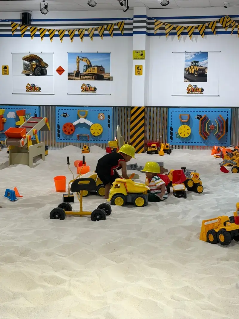 Children filling toy trucks with sand