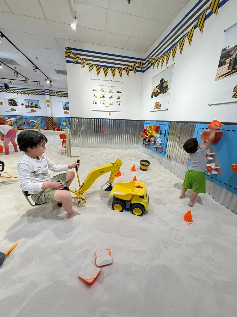 Two children digging together with an excavator