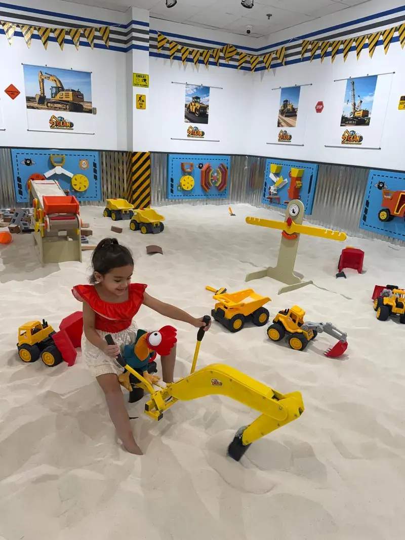 Girl operating a toy excavator arm